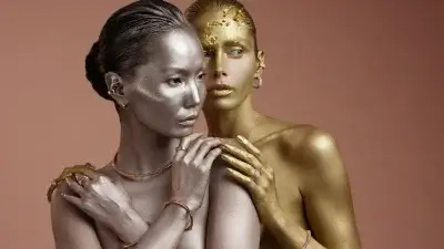 Private Diamond Collection in Dubai Two women pose closely together; one painted silver and the other gold, both adorned with minimalistic jewelry from Fullord, capture attention against a plain, peach-toned background at the Fullord Jewellery Show 2025.